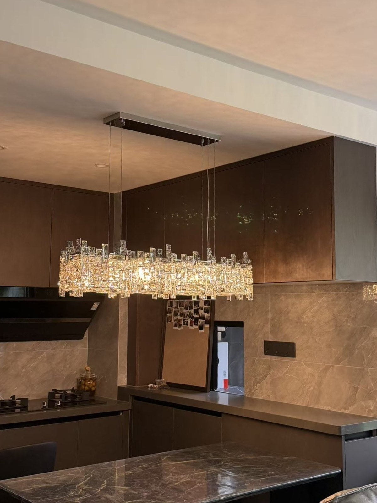 Linear crystal island chandelier over a dark kitchen island