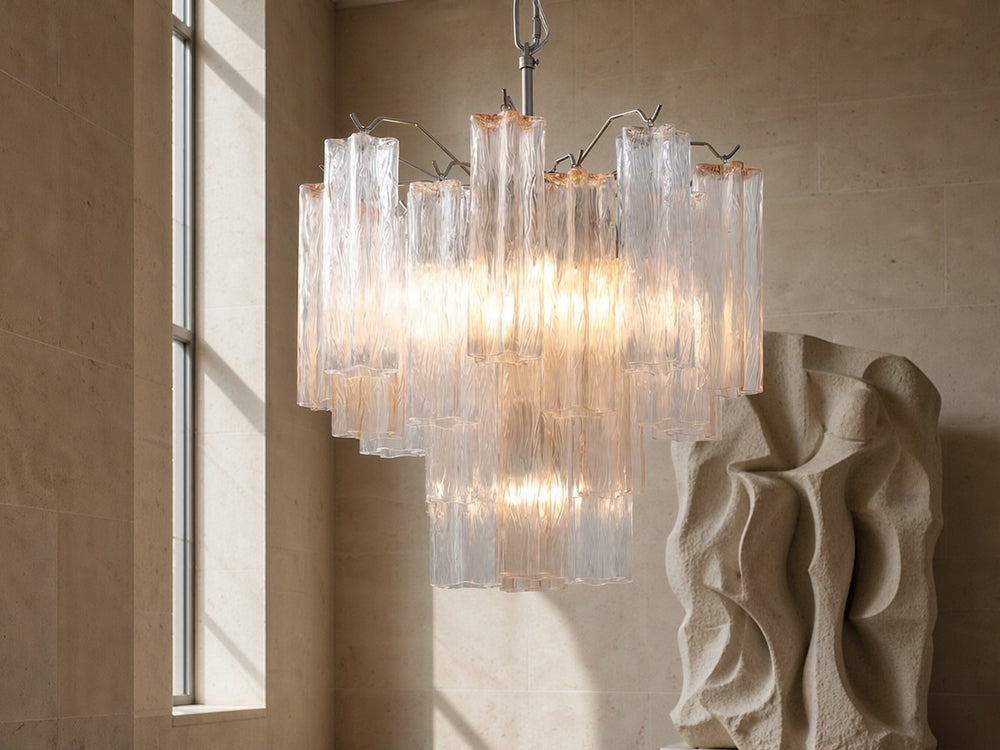 Cascading hand-blown glass chandelier in a limestone hall with a carved stone sculpture